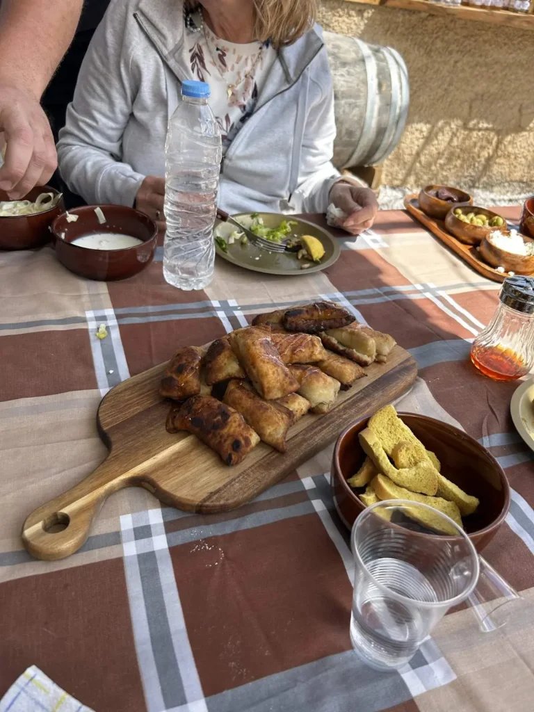 Platter of traditional Cretan pastries and snacks on a checkered tablecloth at Arevitis Farm in Crete, Greece.
