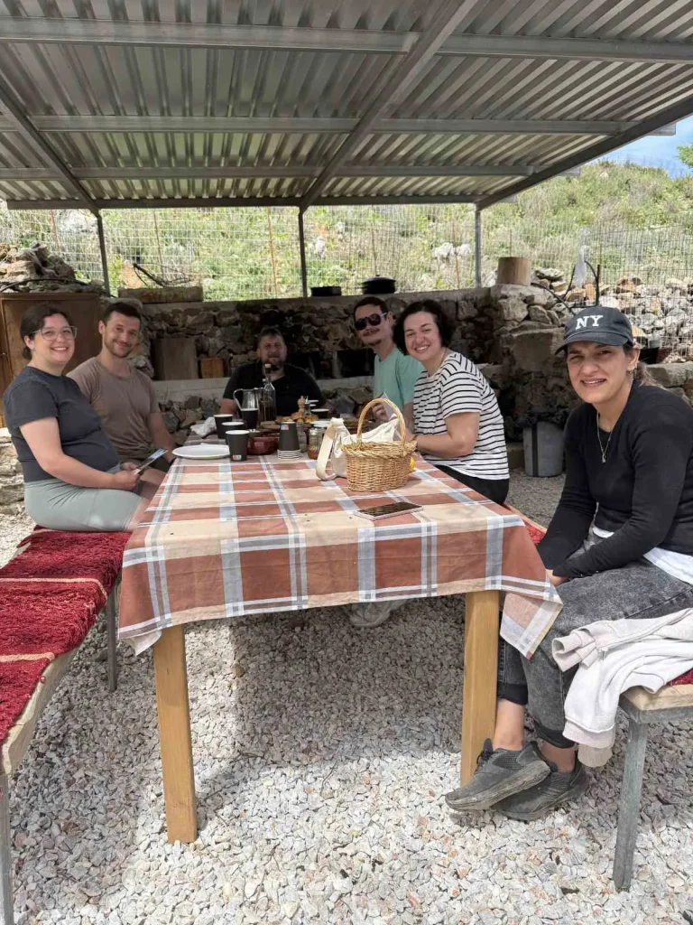Visitors enjoying a traditional Cretan meal together under a shaded patio at Arevitis Farm in Apokoronas.