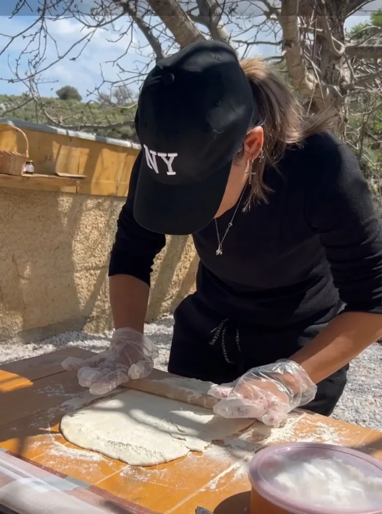 A woman preparing traditional Cretan dough outdoors during a hands-on cooking activity at Arevitis Farm in Apokoronas, Crete.